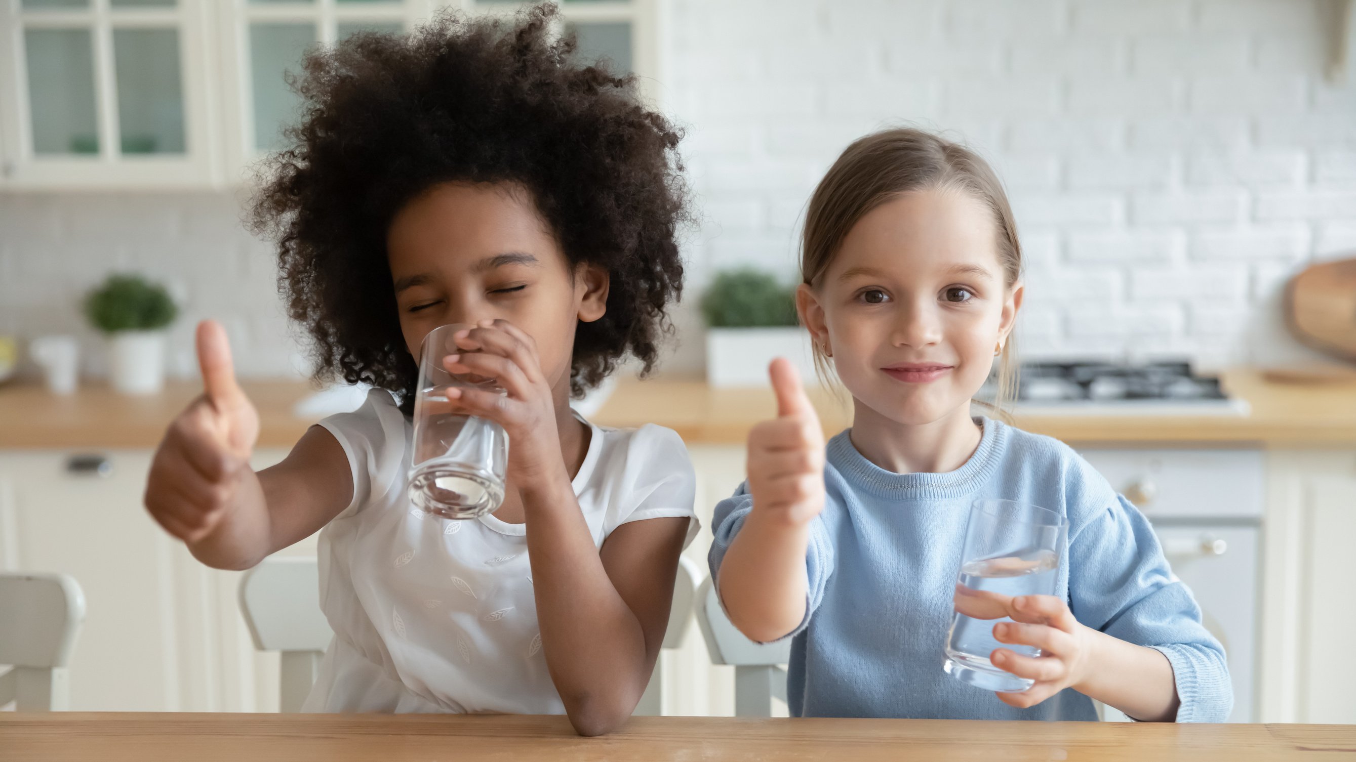 Portrait of happy multiracial children enjoying drinking water.